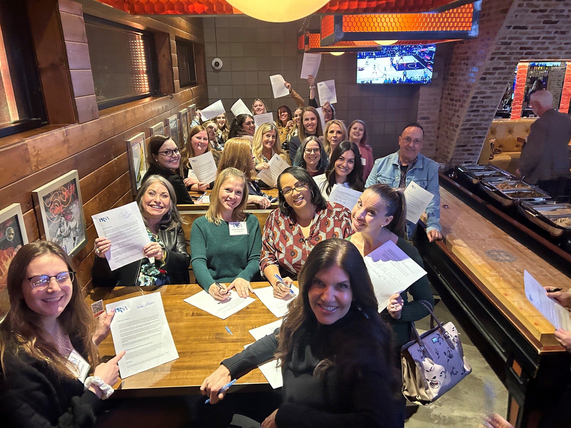 Group of people at tables holding and signing copies of the PRSA Code of Ethics